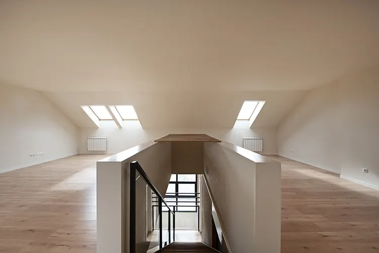 empty-attic-with-chestnut-laminate-flooring-sloping-ceilings-skylights-stairs-down-with-metal-glass-railing
